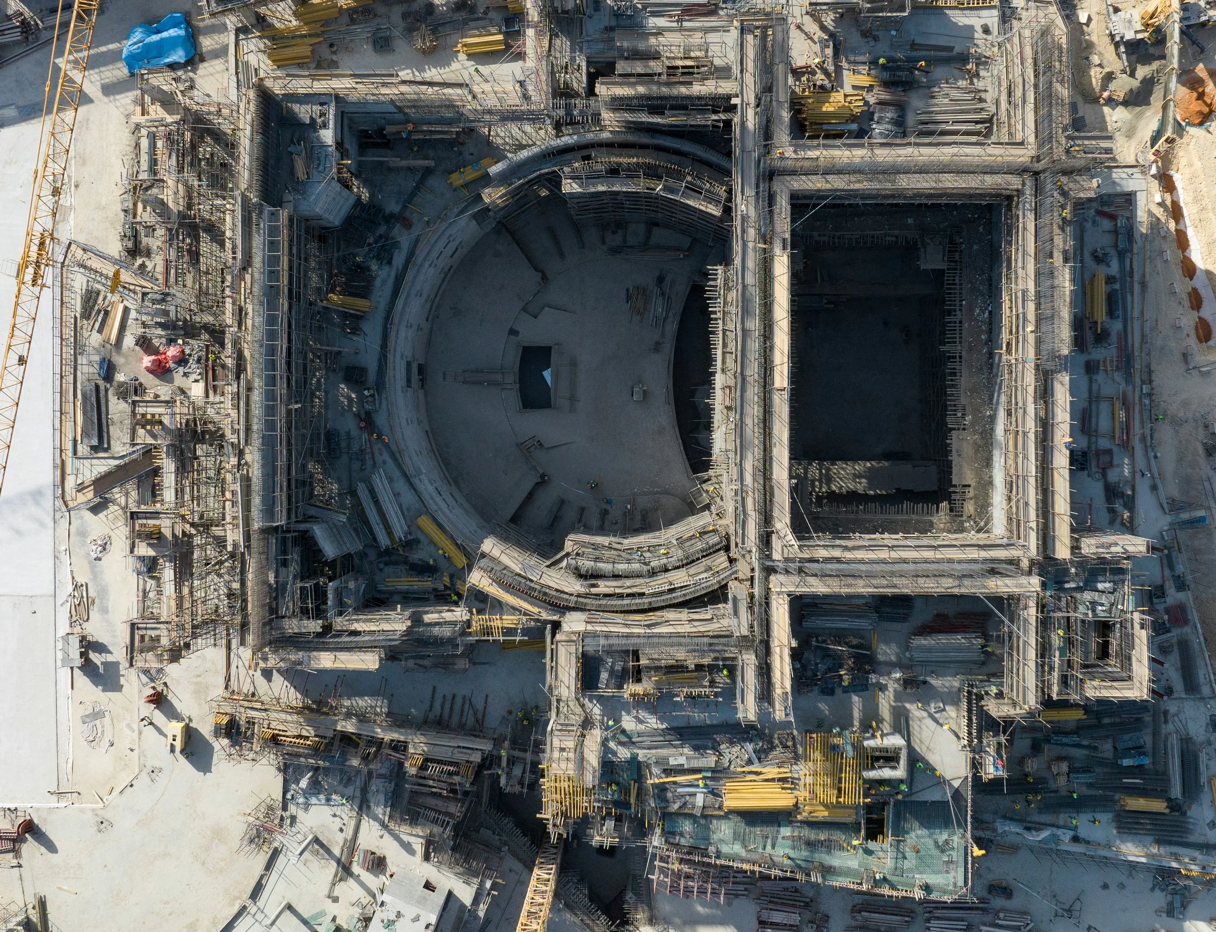 Aerial view of a construction site with two large foundation structures, construction materials, equipment, and scaffolding.