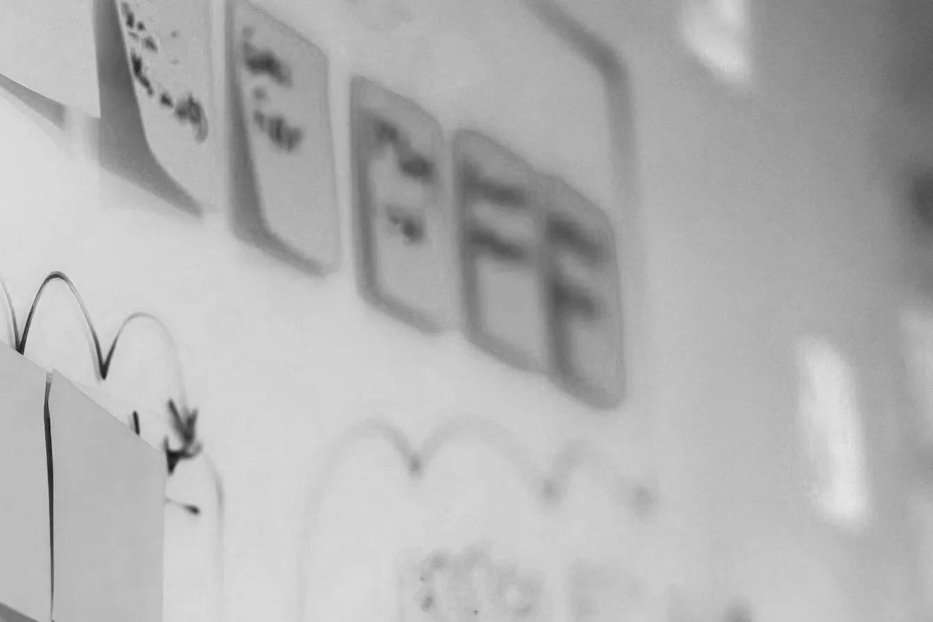 Close-up of a whiteboard with blurred sticky notes and drawings of hearts in black marker.