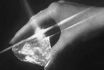 Hand holding a large, faceted diamond