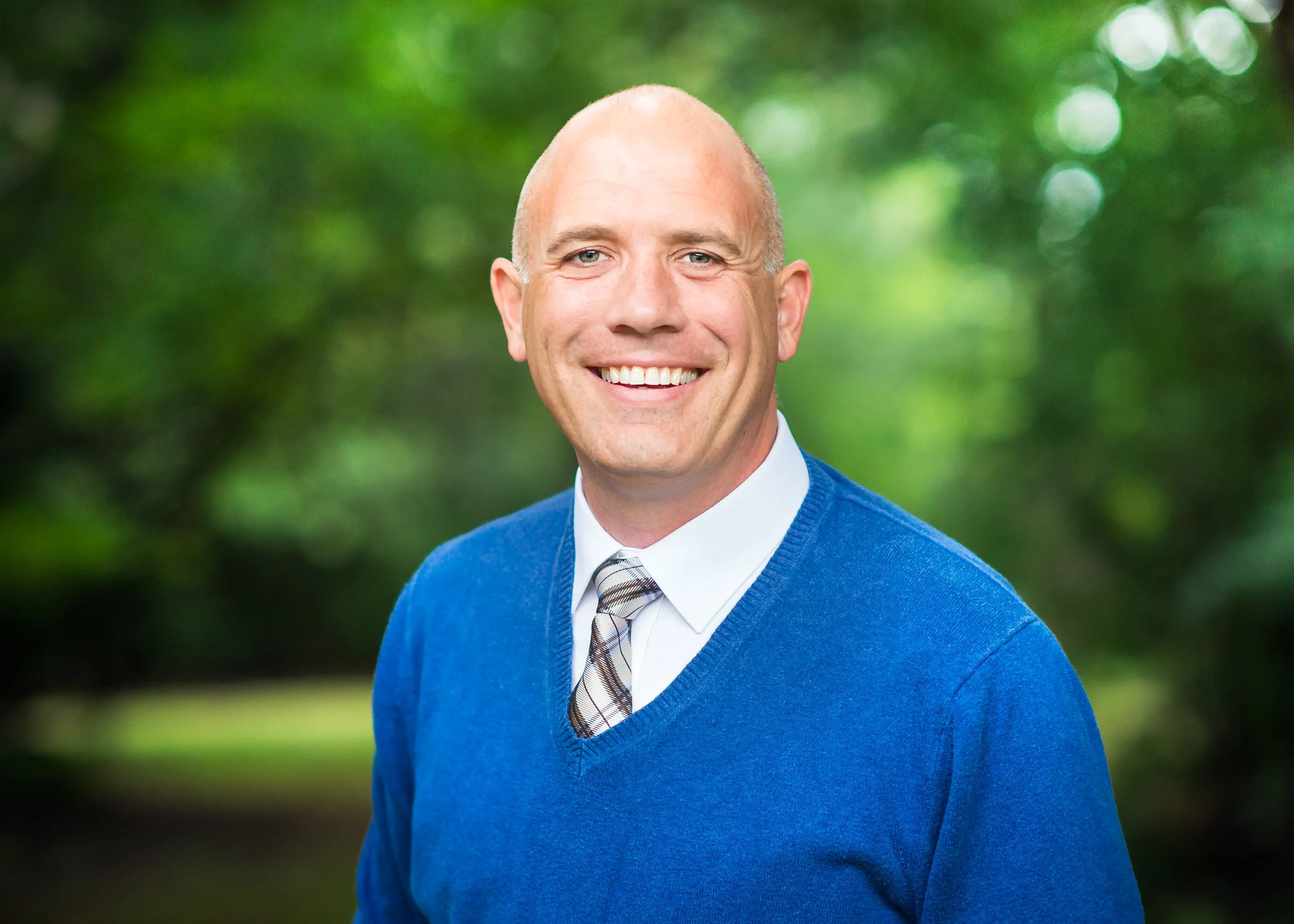 Luke Bruschuk, therapist at Cherry Hill Counseling, smiling outdoors in a blue sweater and tie.