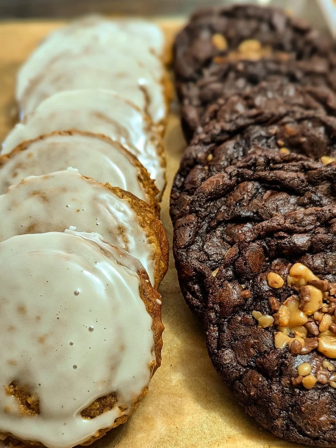Close-up of a tray with cookies, including frosted sugar cookies on the left and chocolate cookies with nuts on the right.