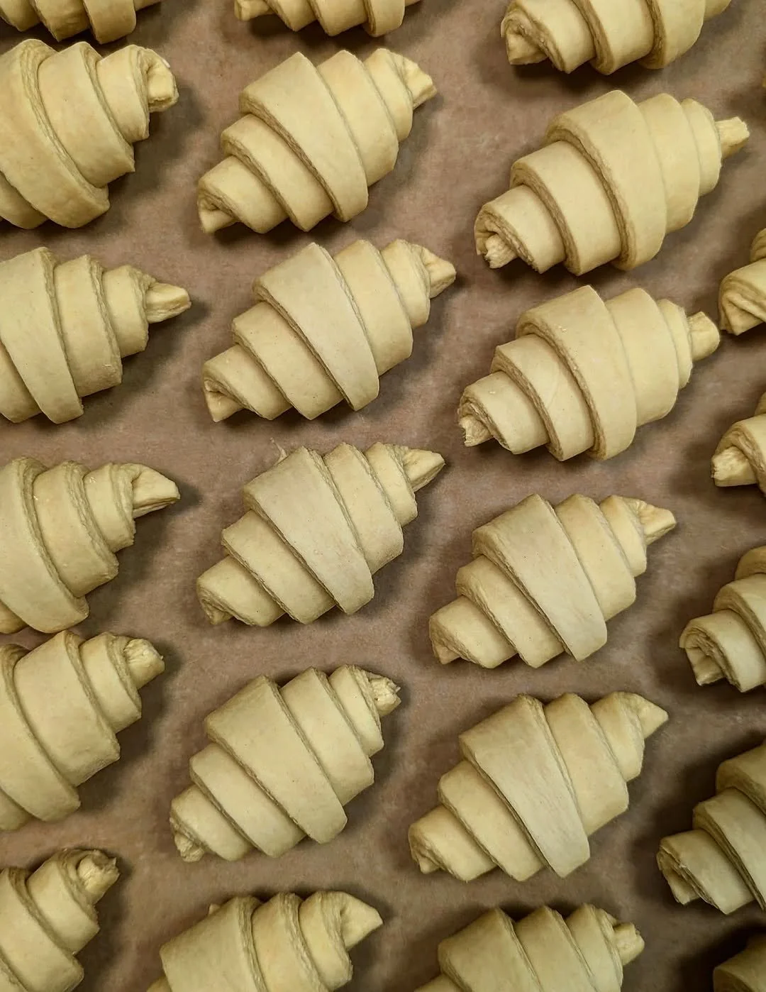 Unbaked croissants arranged on baking sheet lined with parchment paper.