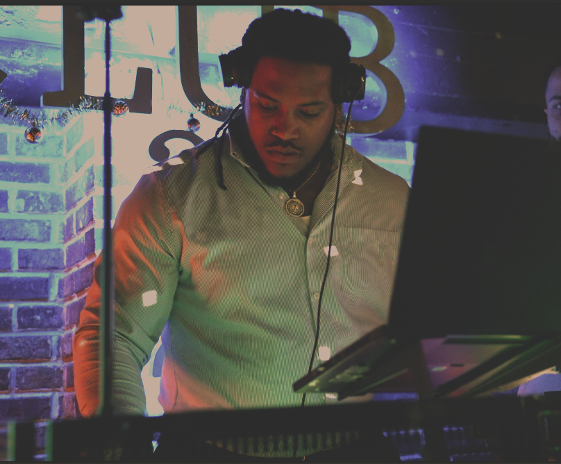 DJ Isaiah wearing headphones and a button-up shirt, mixing in Club 224 at Lucky's Downtown.