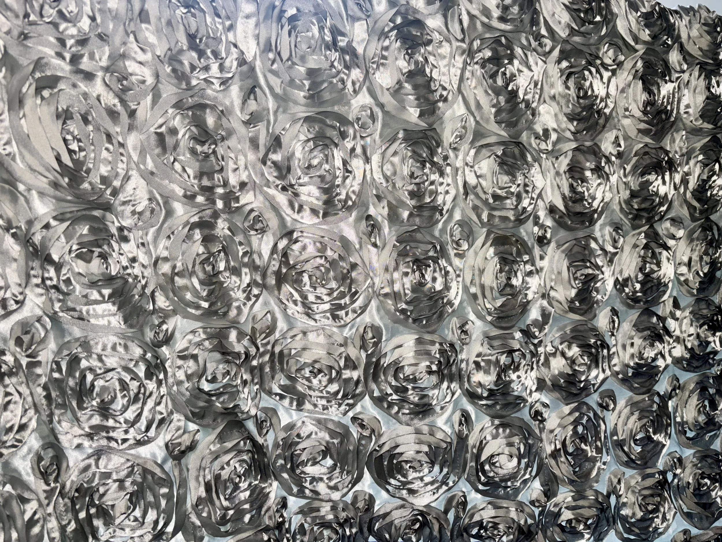 A textured surface made of numerous silver metallic roses arranged in a grid pattern.