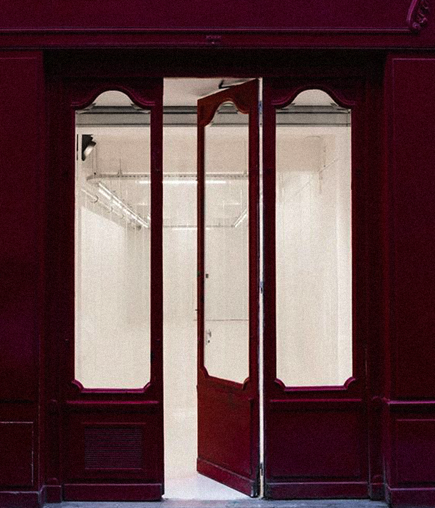 Open wooden closet door revealing a walk-in closet with white walls and wire shelving.