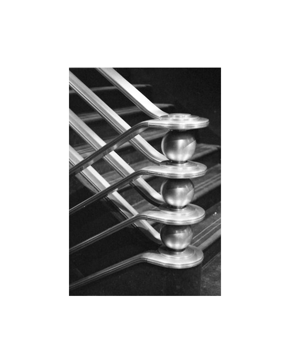 Close-up of metallic hardware, possibly a hinge or a mechanical part, with multiple rounded joints connected by straight and curved metal bars, reflected on a glossy surface.