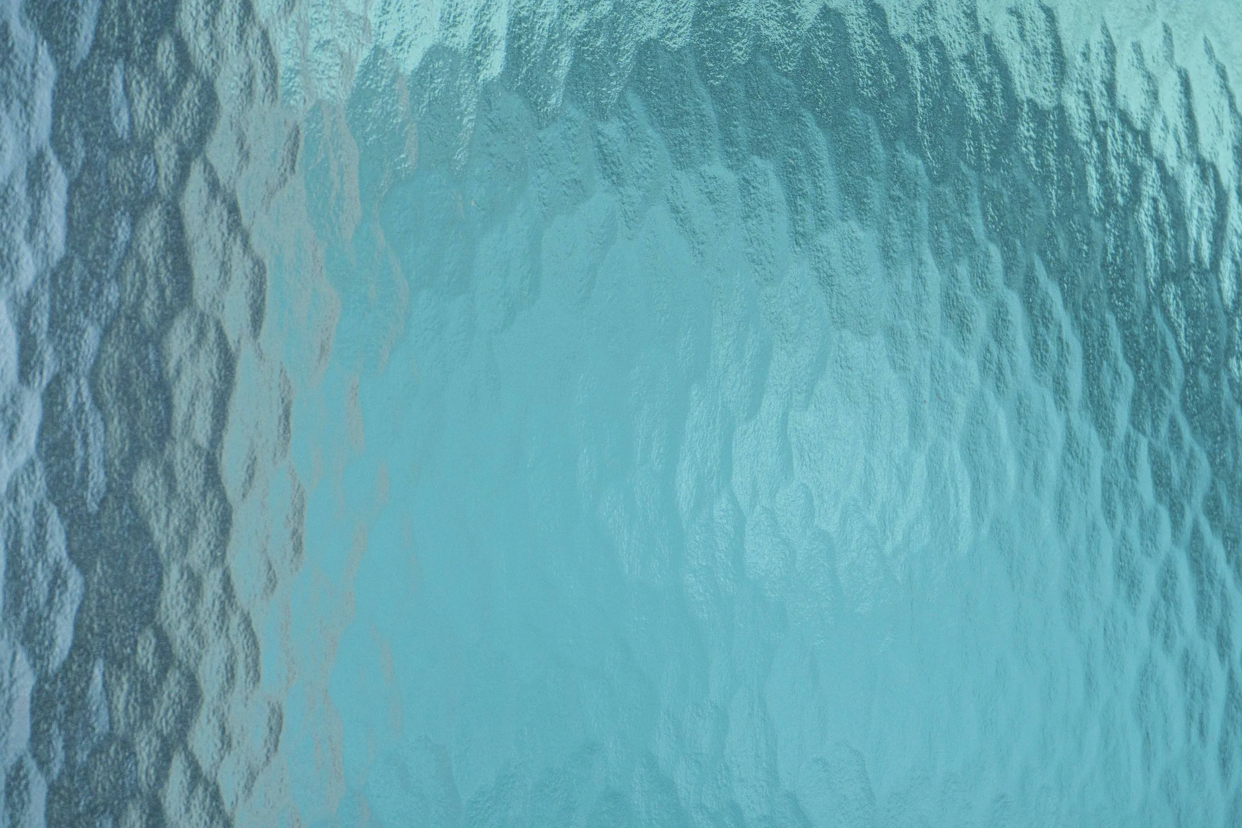 Close-up of a textured, turquoise-colored surface, possibly water or a painted surface.