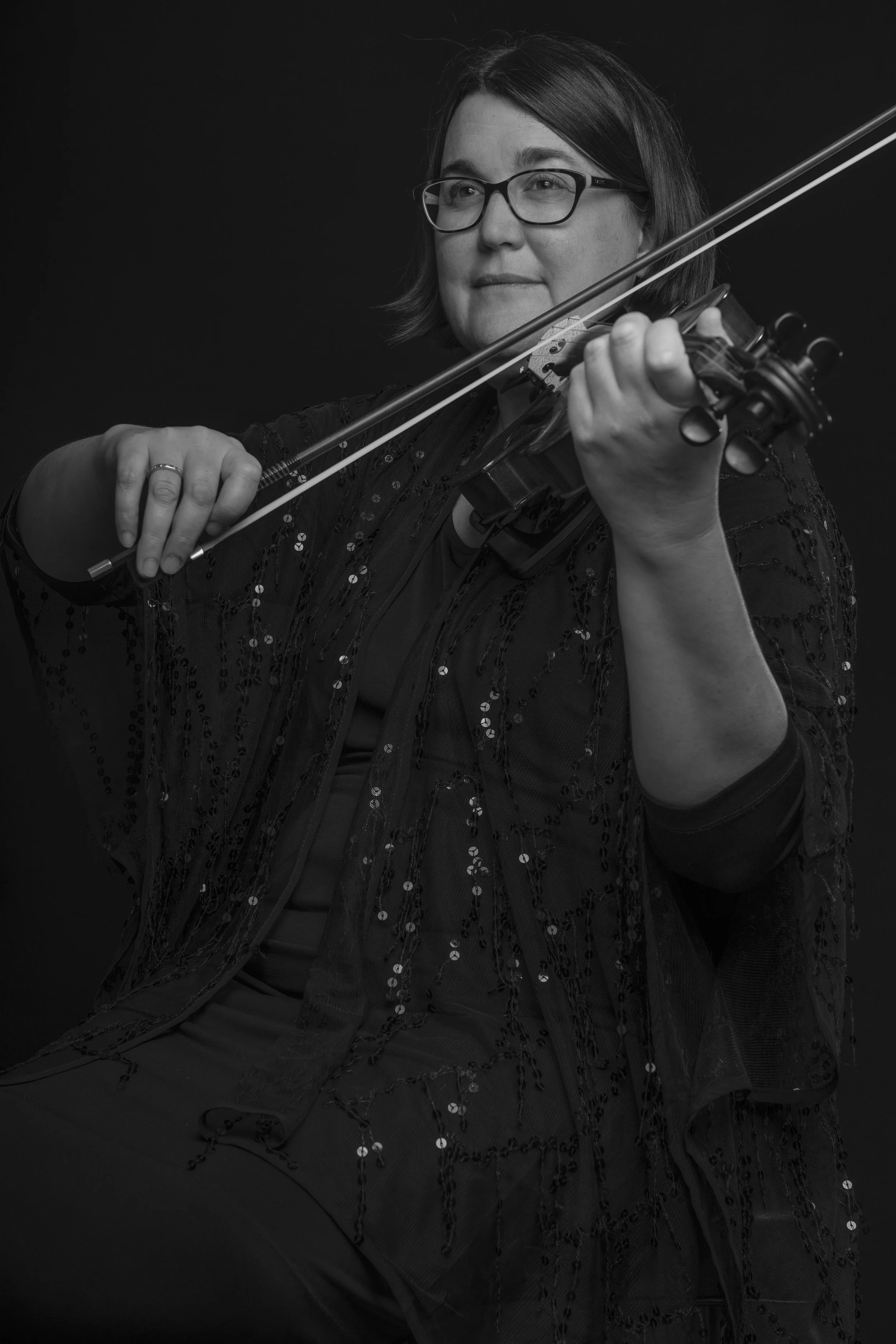 Black and white photograph of a woman with glasses playing a violin.