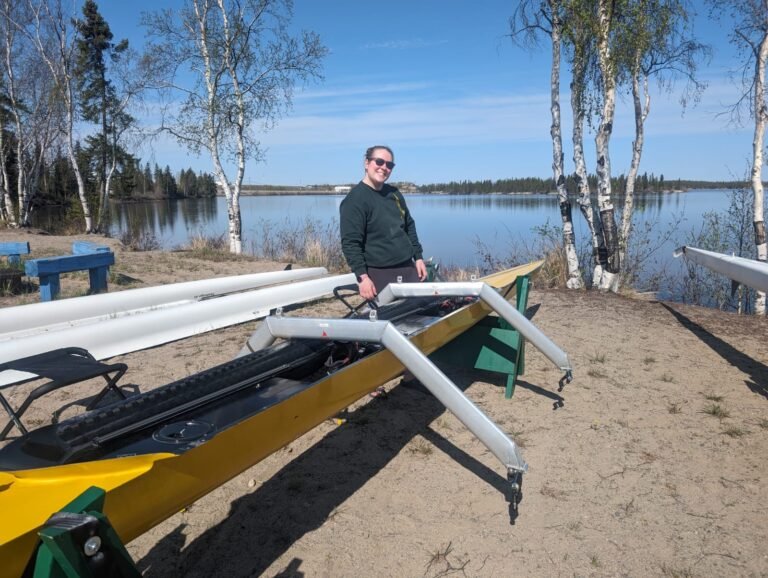 Woman with a green sweatshirt next two a yellow rowing boat for two people.