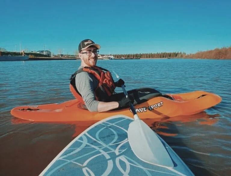 A man in an orange kayak in the water.