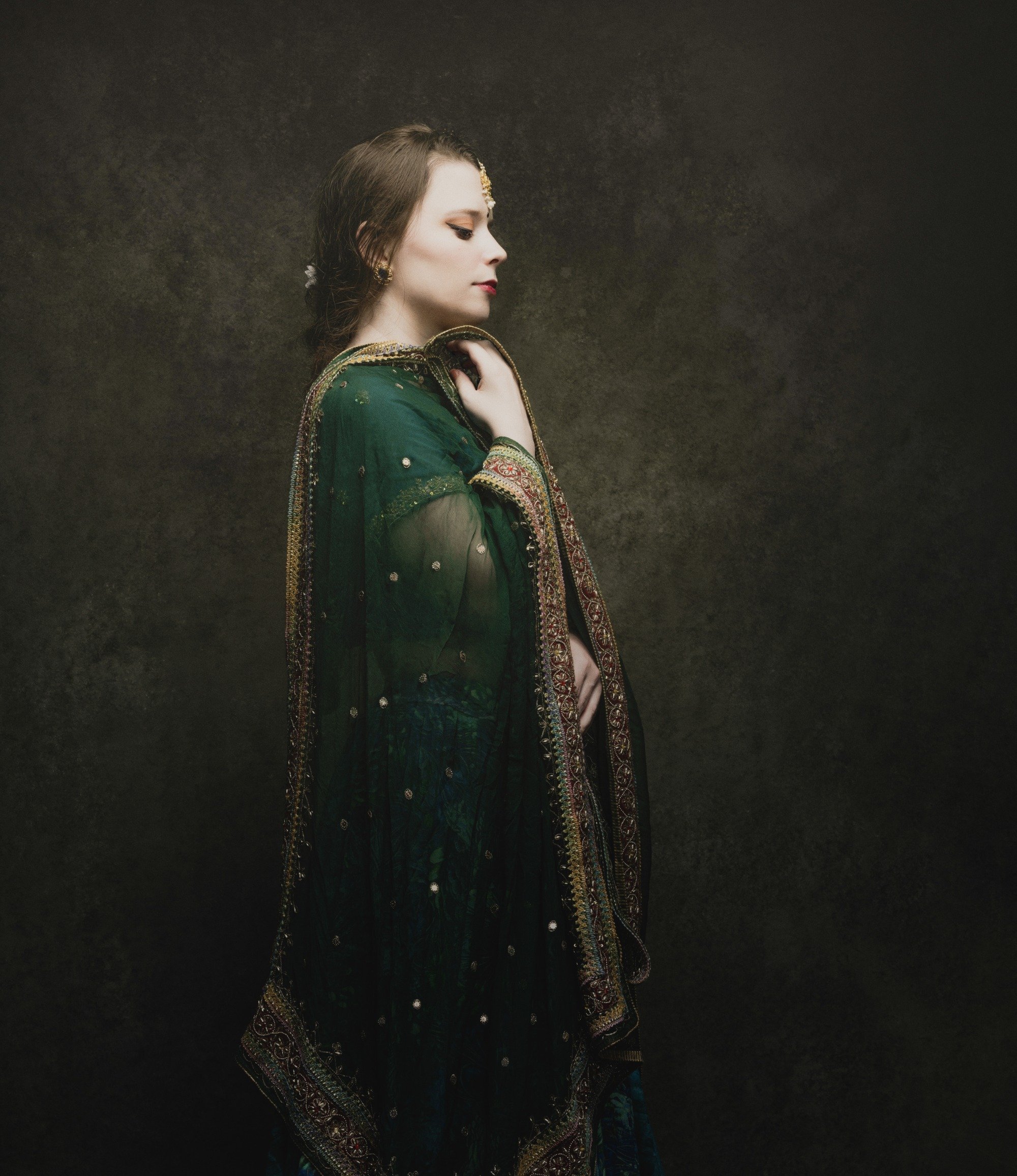 Mouki pose de profil avec son dupatta vert drapé sur ses épaules, yeux fermés