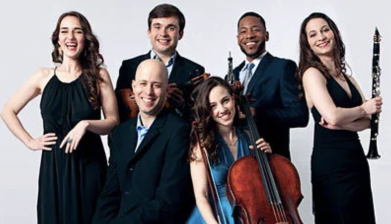 Six members of Shuffle Concert ensemble posing together with string instruments in a studio portrait.