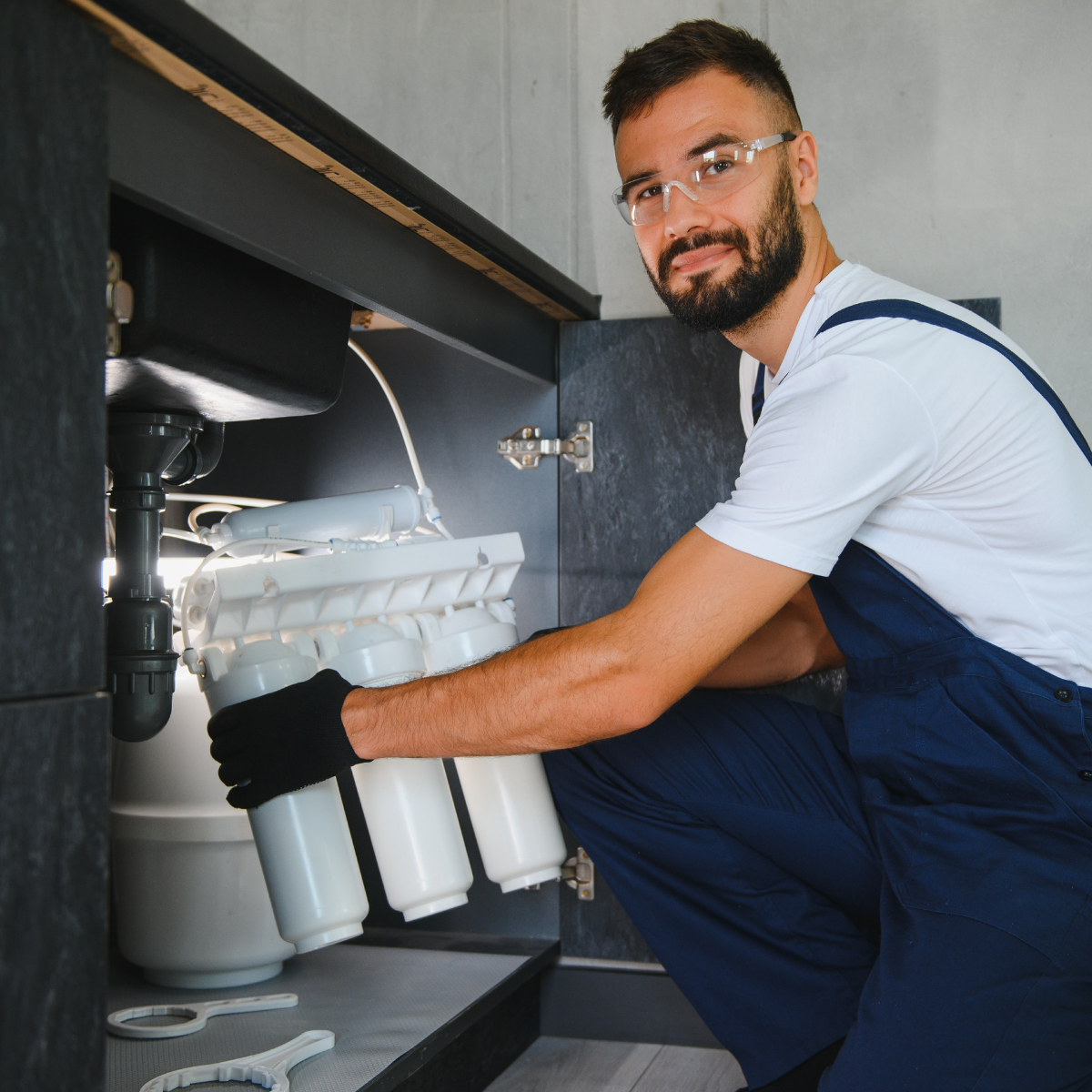 A technician installing a water filter under a kitchen sink.