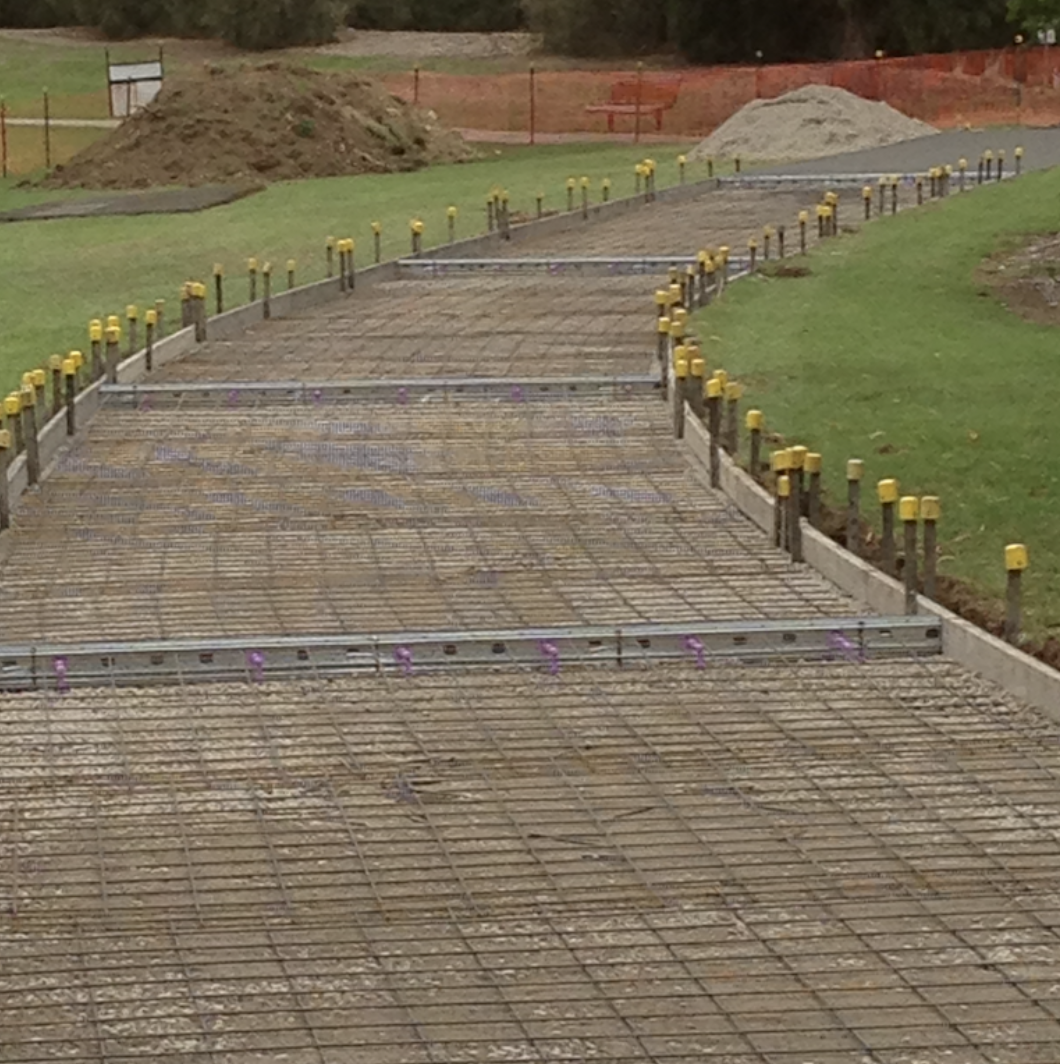 Concrete foundation with rebar and yellow protective caps for a construction project in progress.