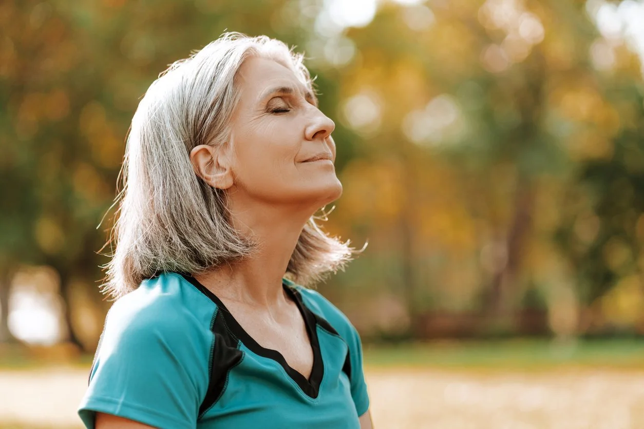 Woman standing outside with eyes closed and peaceful expression