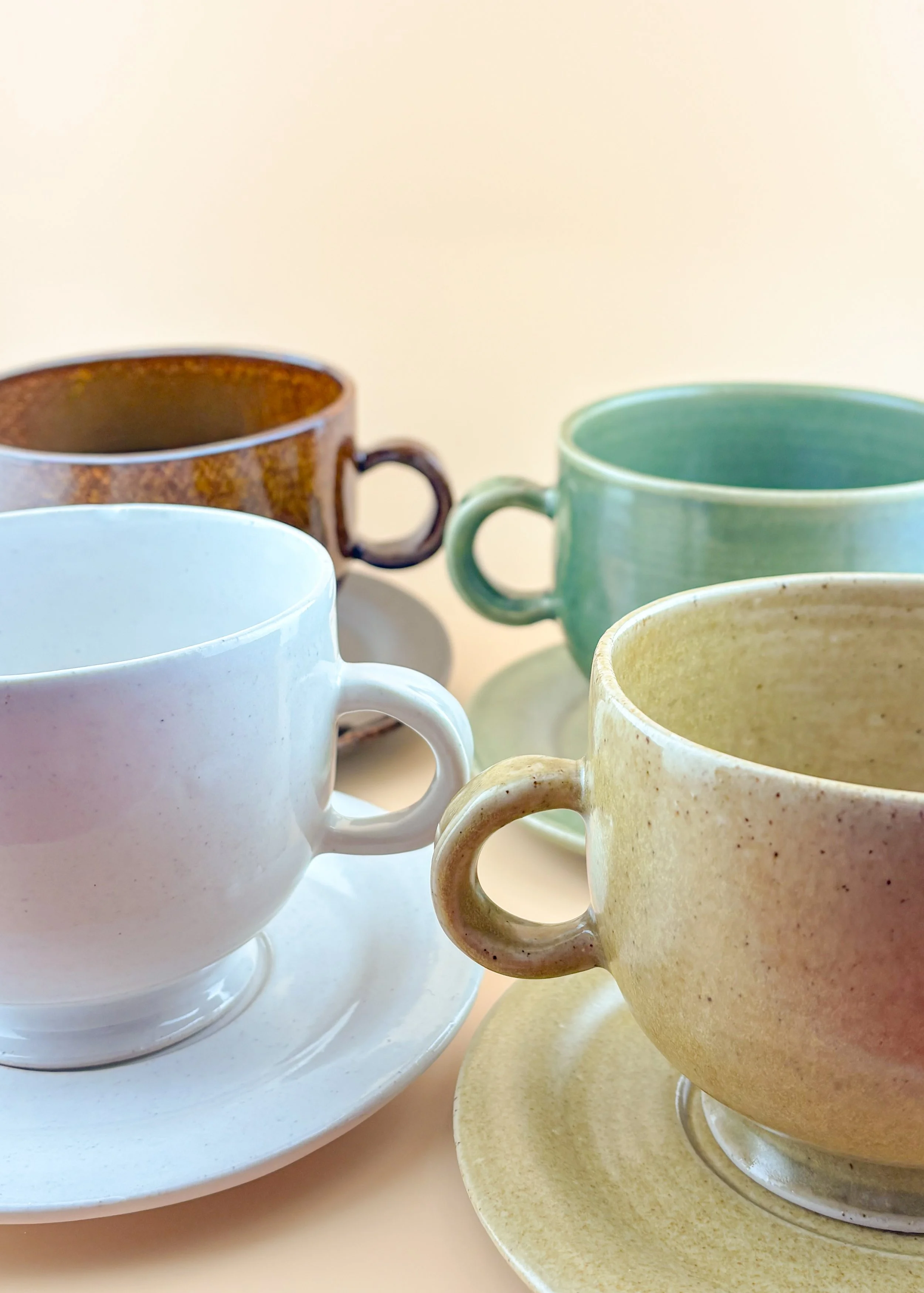 Close-up lineup of ceramic matcha mugs showing glaze variation and smooth lip.
