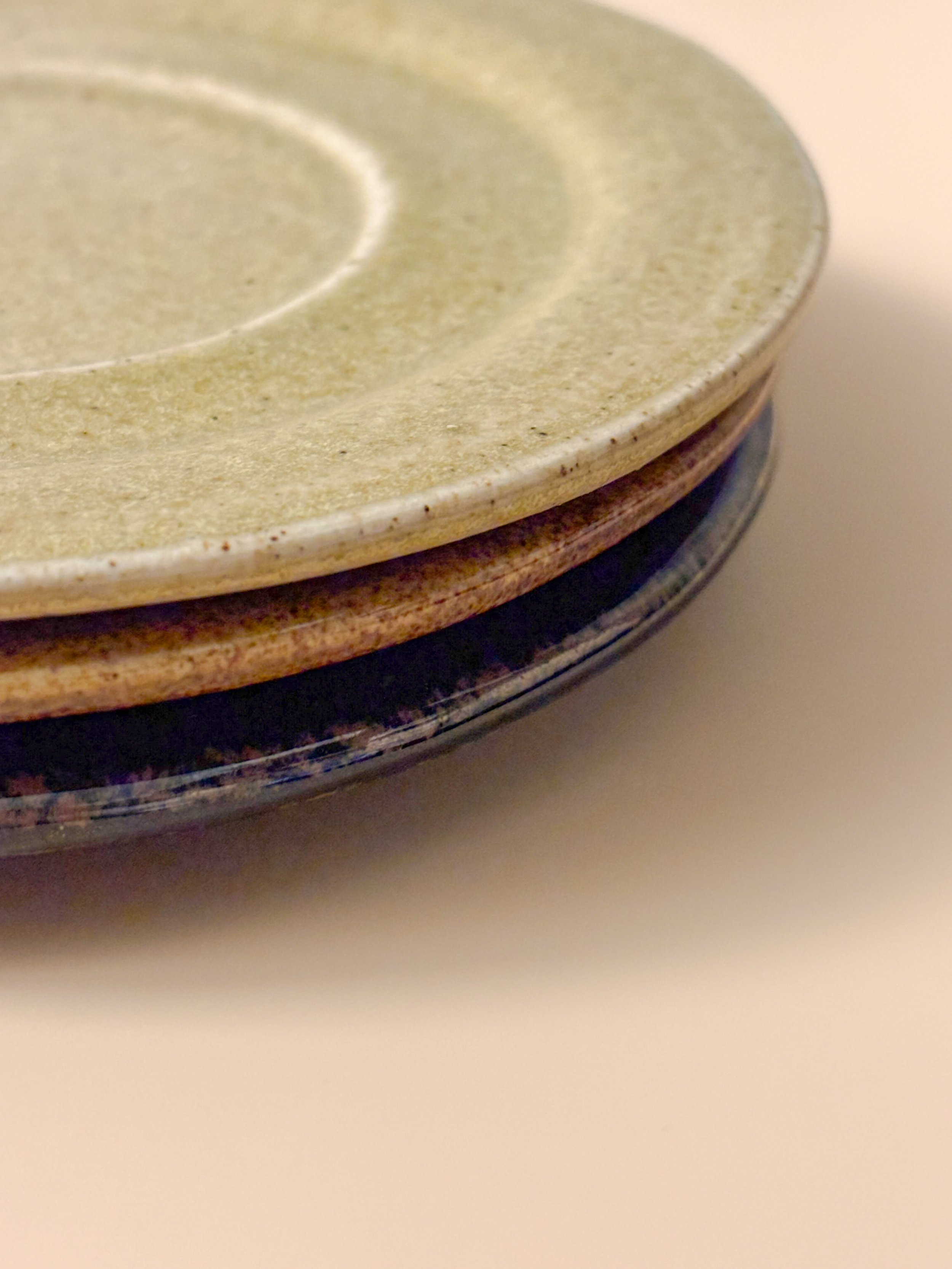 Close-up of stacked handmade ceramic saucers showing glaze texture and layered edges.JPG