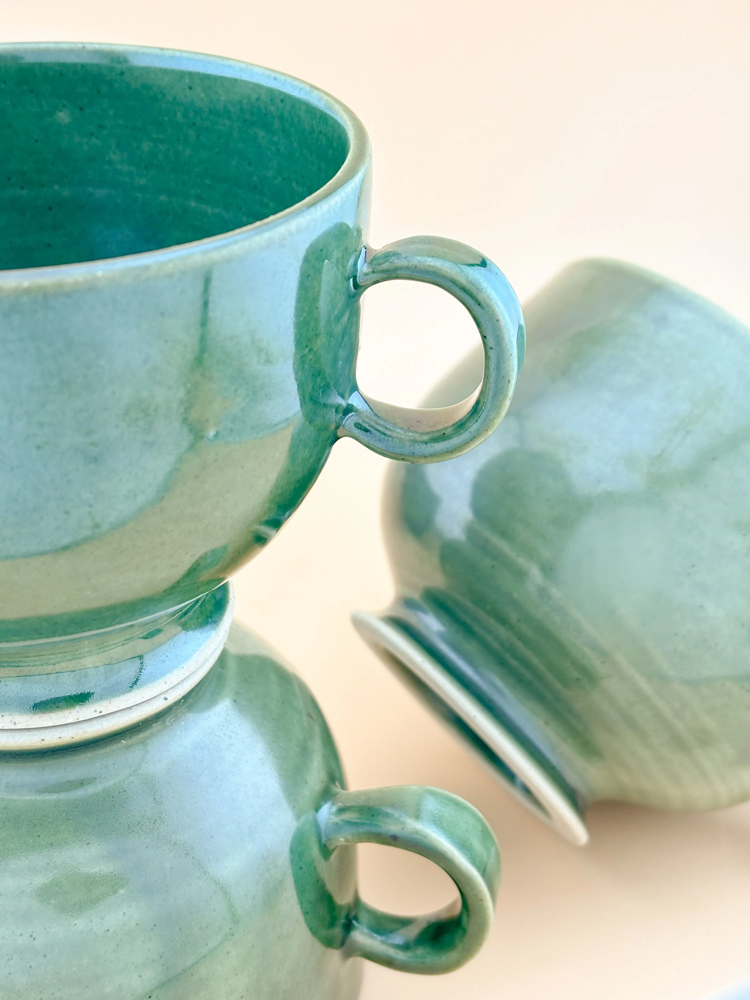 Handmade ceramic matcha mugs in Ceremonial Jade glaze, showcasing curved shape and modern handle inspired by traditional matcha bowls.