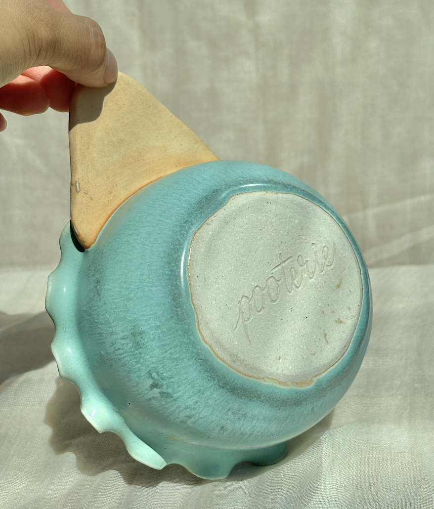 Underside of a handmade ceramic mint waffle cone bowl showing the Pooterie maker's mark, held in hand.png