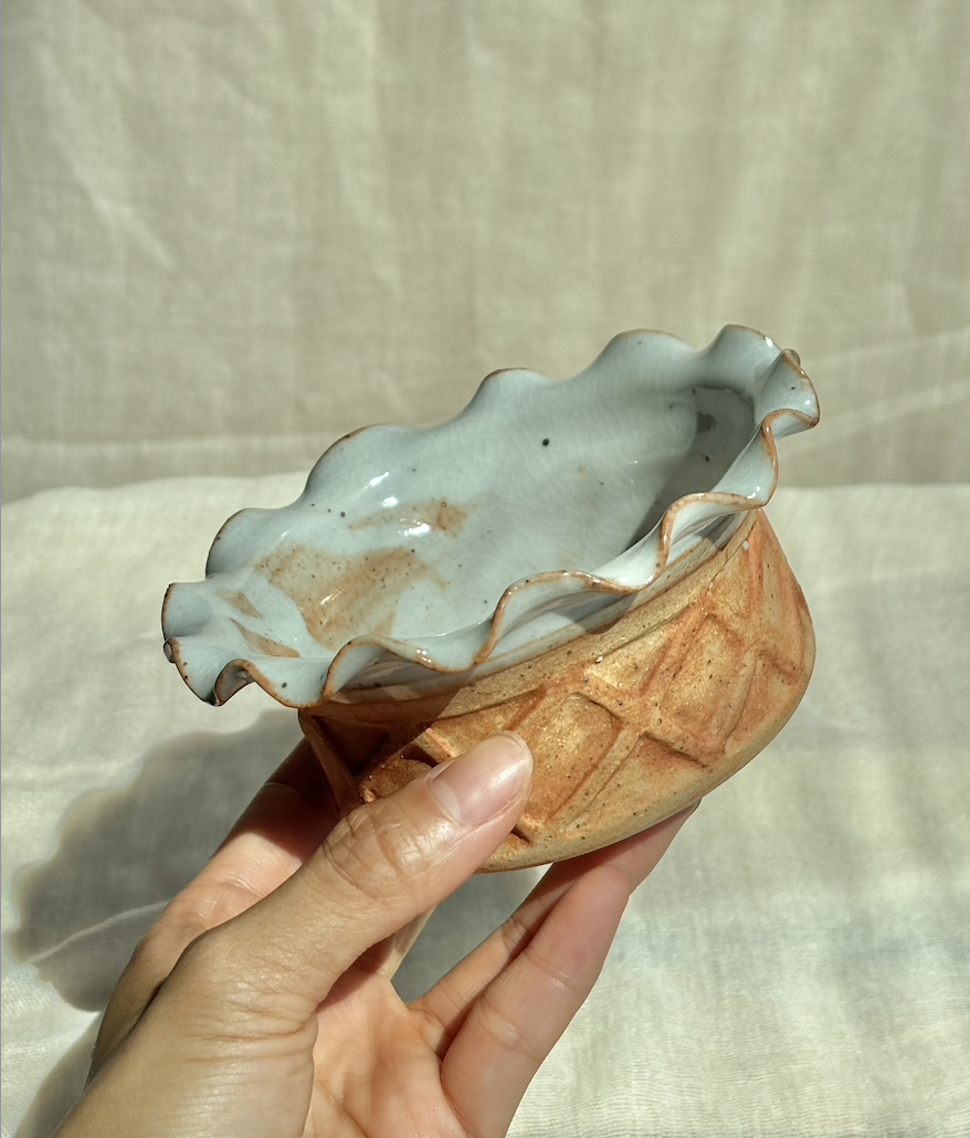 Handmade ceramic salted caramel waffle cup ice cream bowl with ruffled rim, held in hand.png