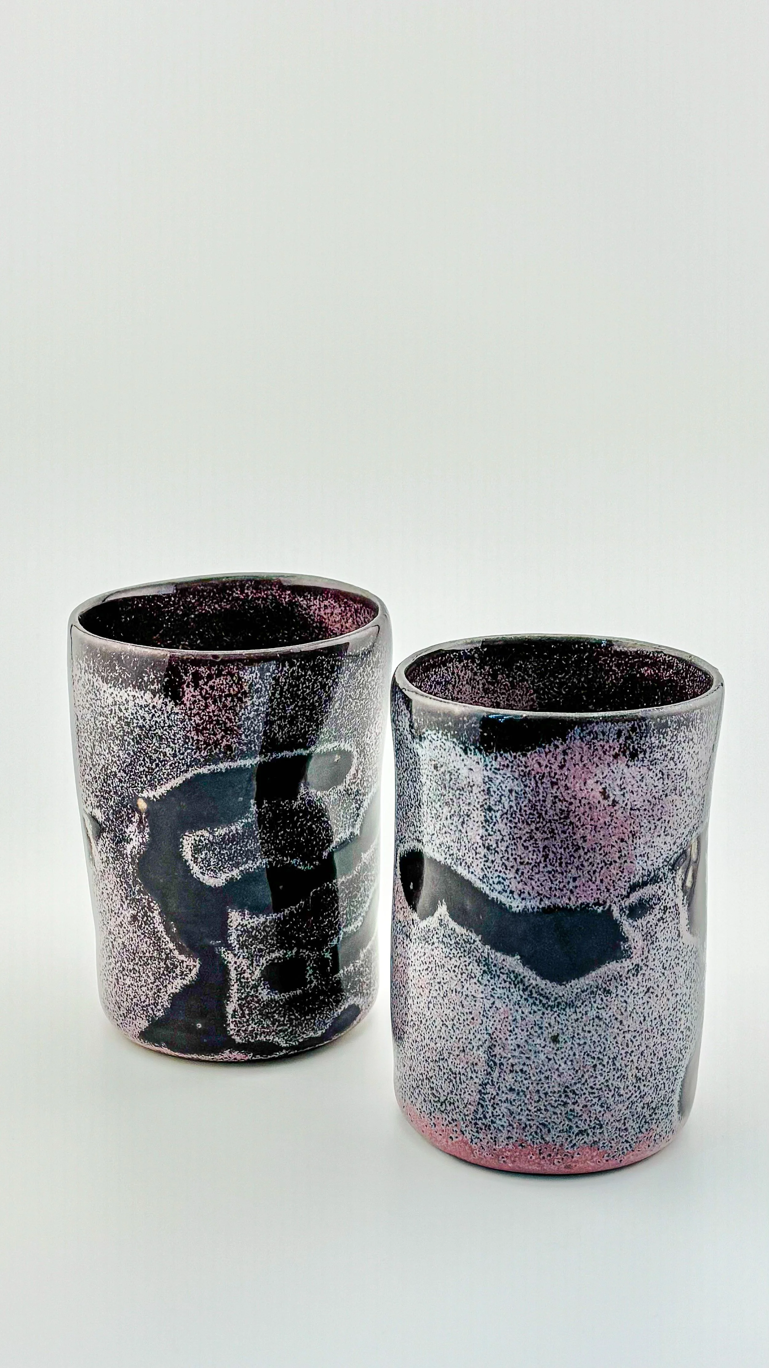 Pair of wheel-thrown ceramic tumblers in deep purple and cosmic pink reduction glaze, handmade stoneware, small batch artisan pottery.JPG