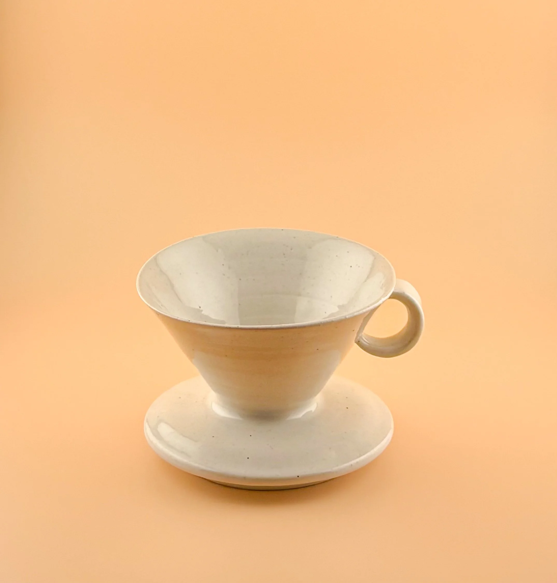 White handmade ceramic pour-over coffee dripper with matching mug and saucer, wheel-thrown with minimalist design.