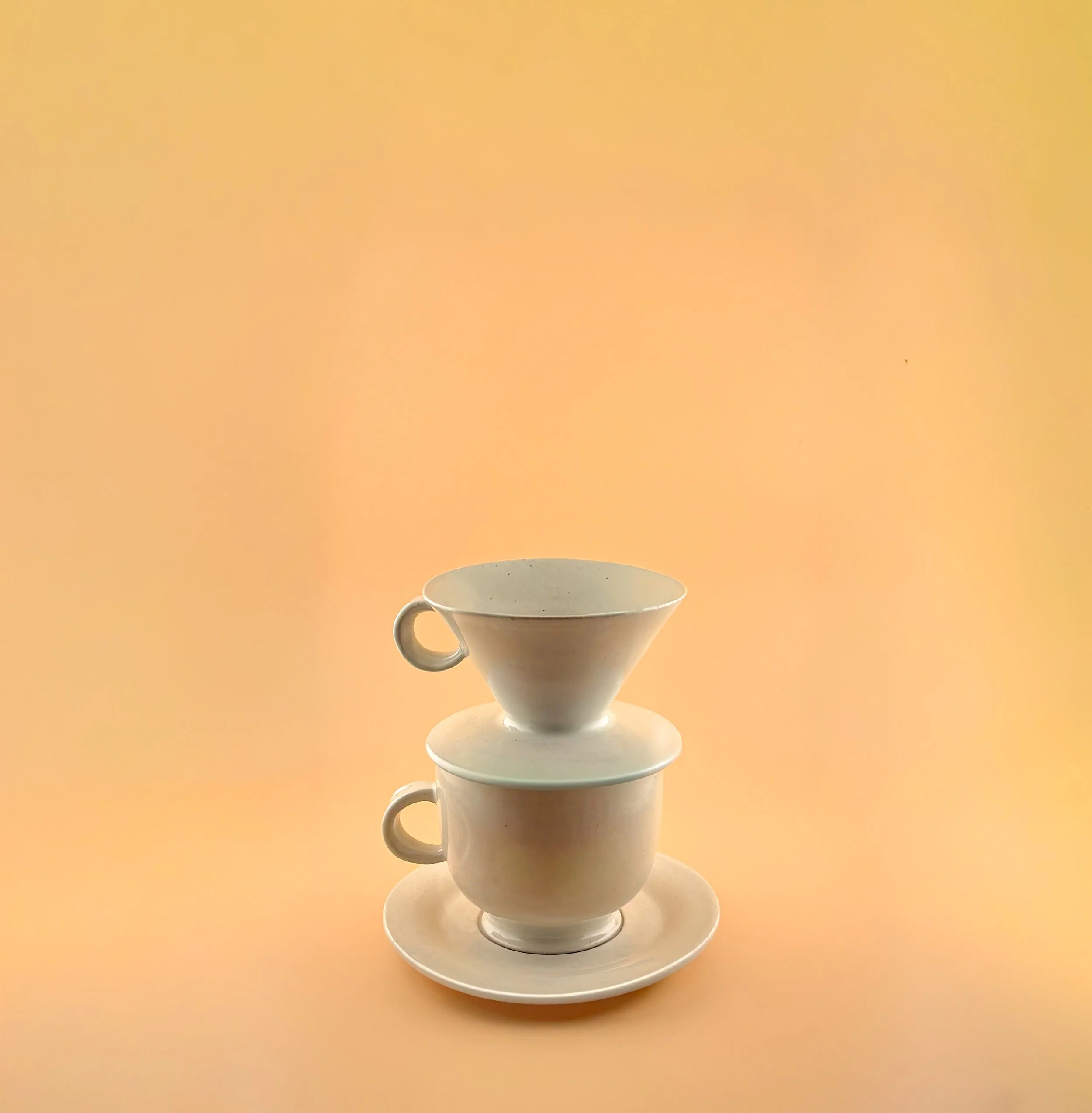 White ceramic pour-over coffee dripper stacked on matching mug, showcasing clean wheel-thrown lines and modern silhouette.
