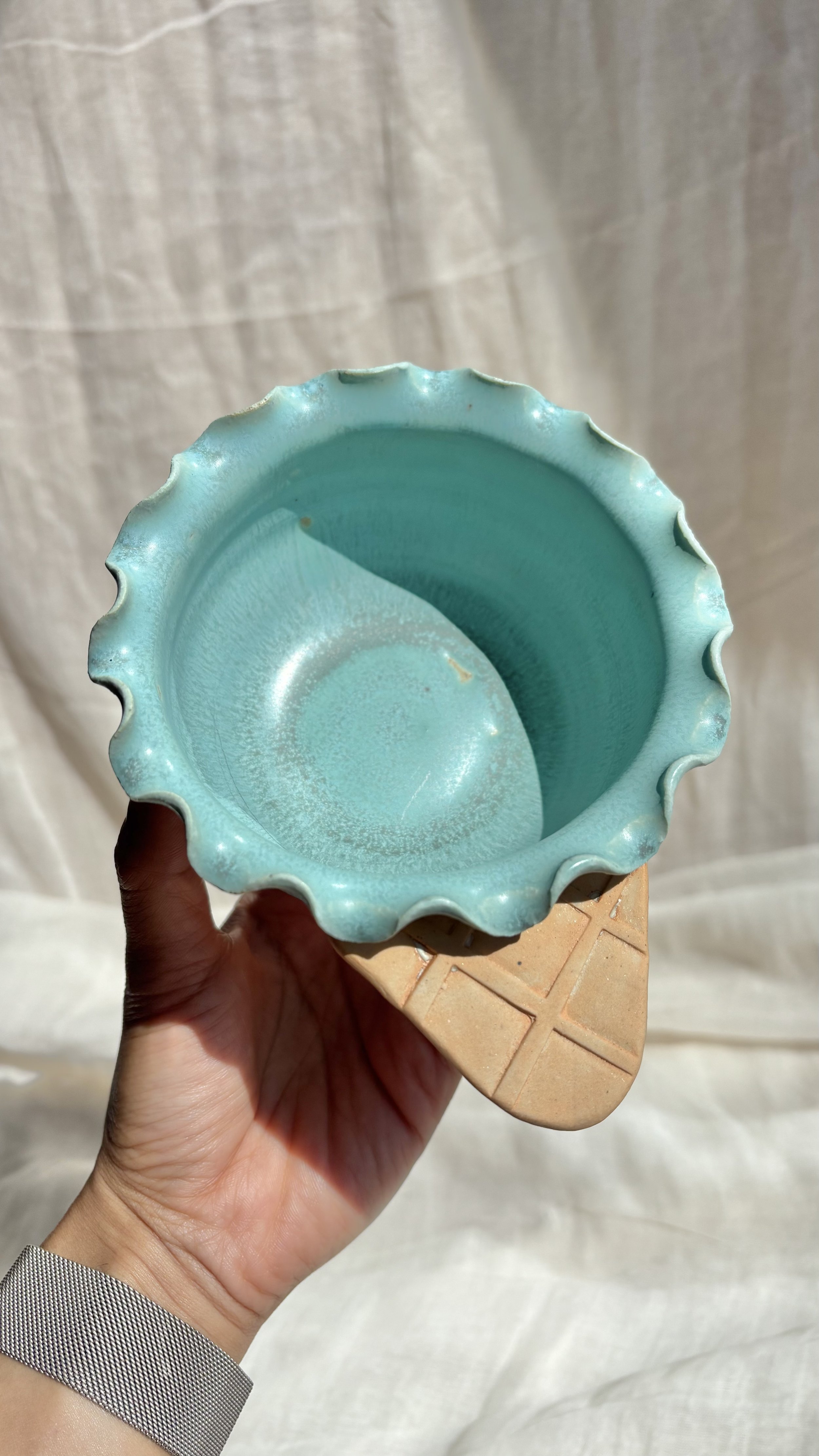 Handmade ceramic mint waffle cone ice cream bowl with ruffled rim, held in hand.jpg
