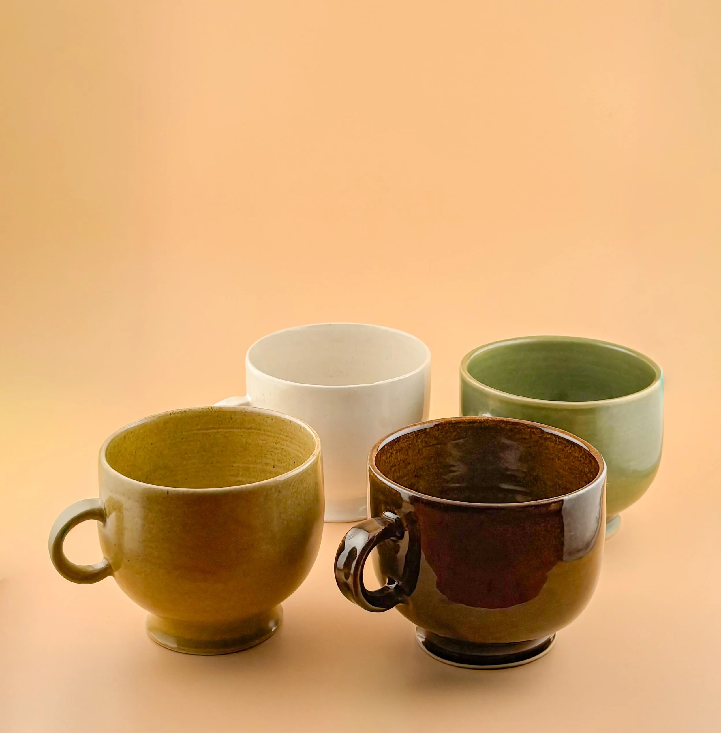 Group of ceramic matcha mugs in all four Rituals glazes arranged together.