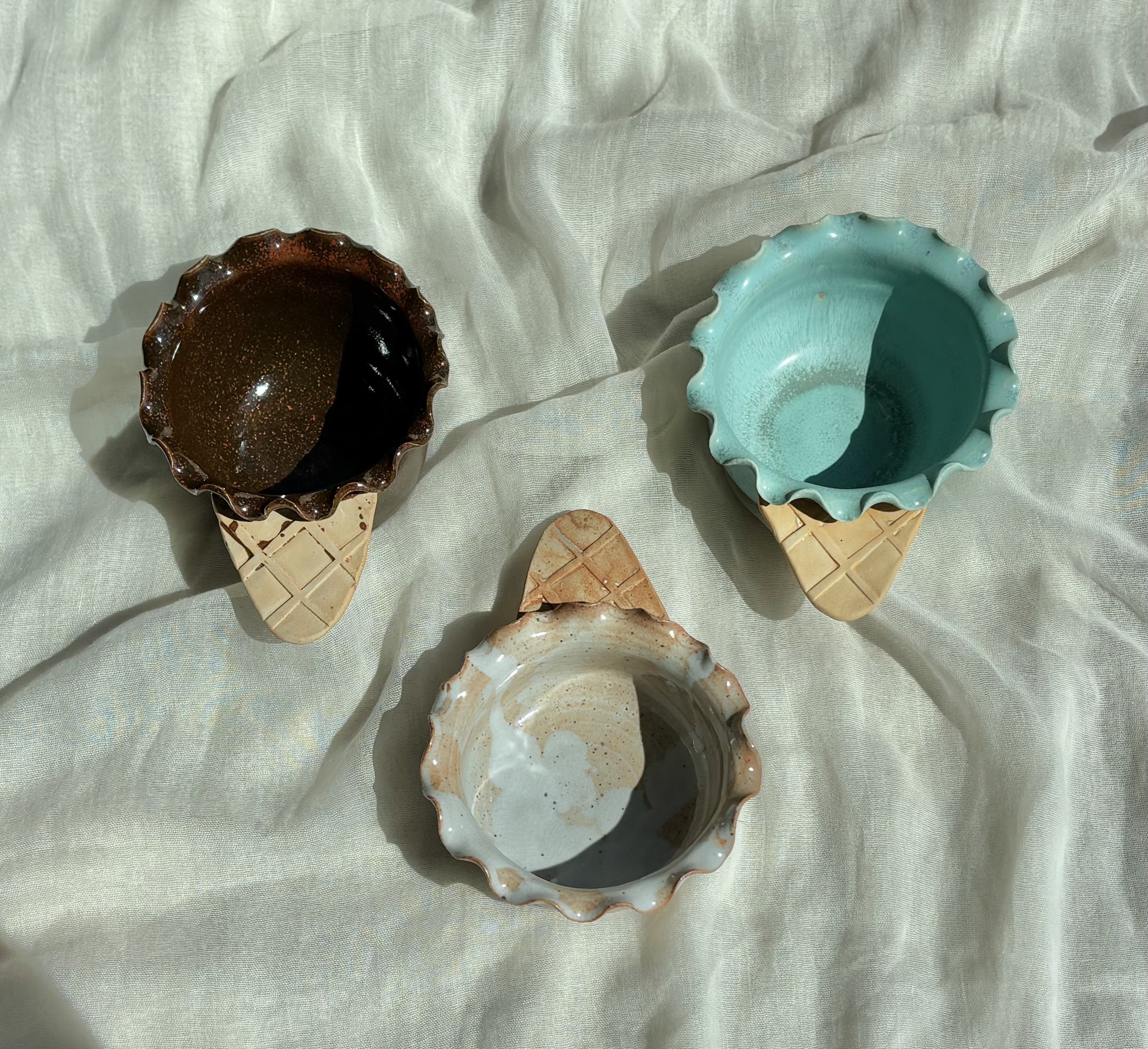 Handmade ceramic waffle cone ice cream bowls in chocolate brownie, mint, and salted caramel on soft linen.jpg