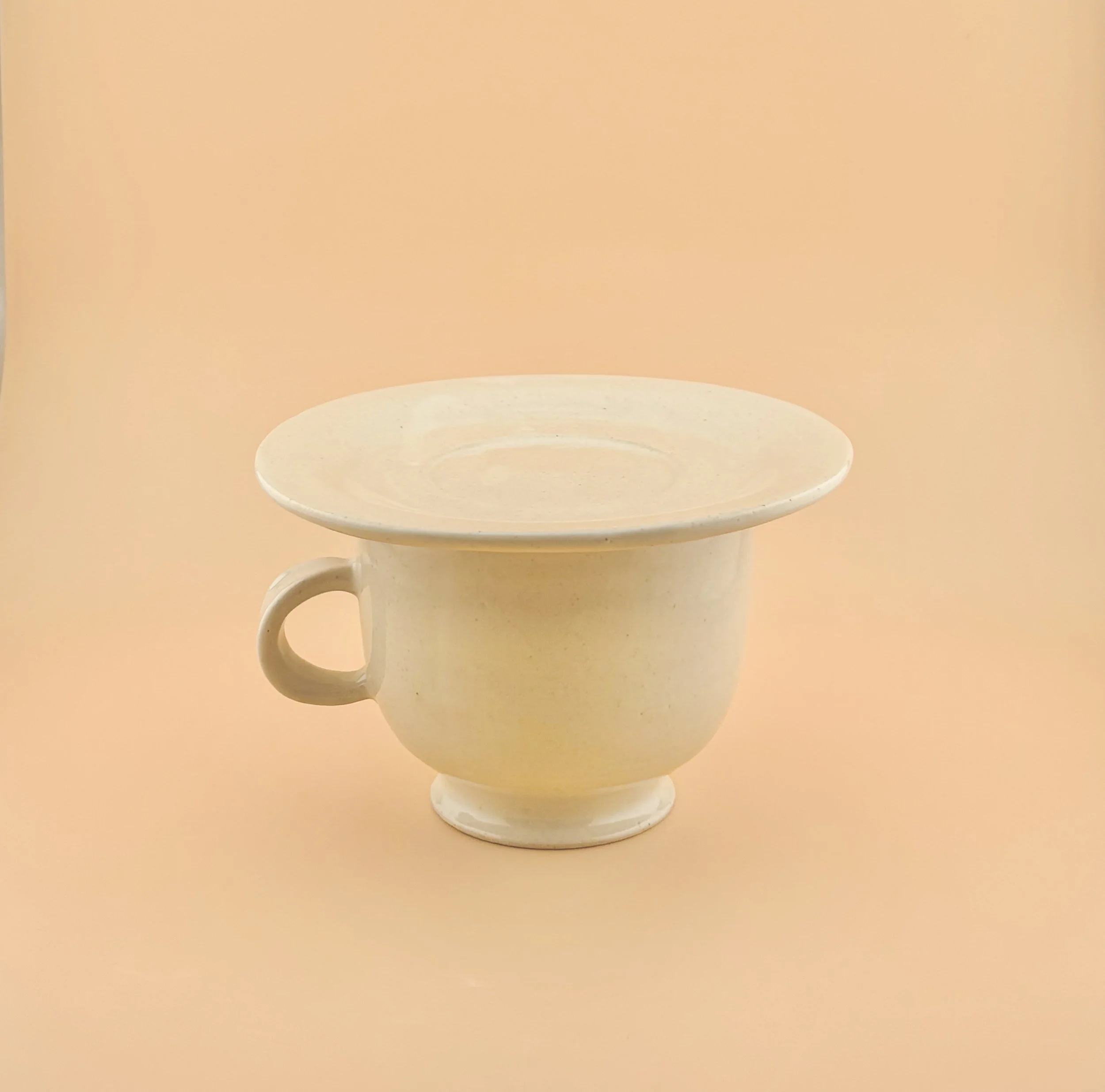 White ceramic multi-use saucer used as a lid resting on a matcha mug, wheel-thrown stoneware.