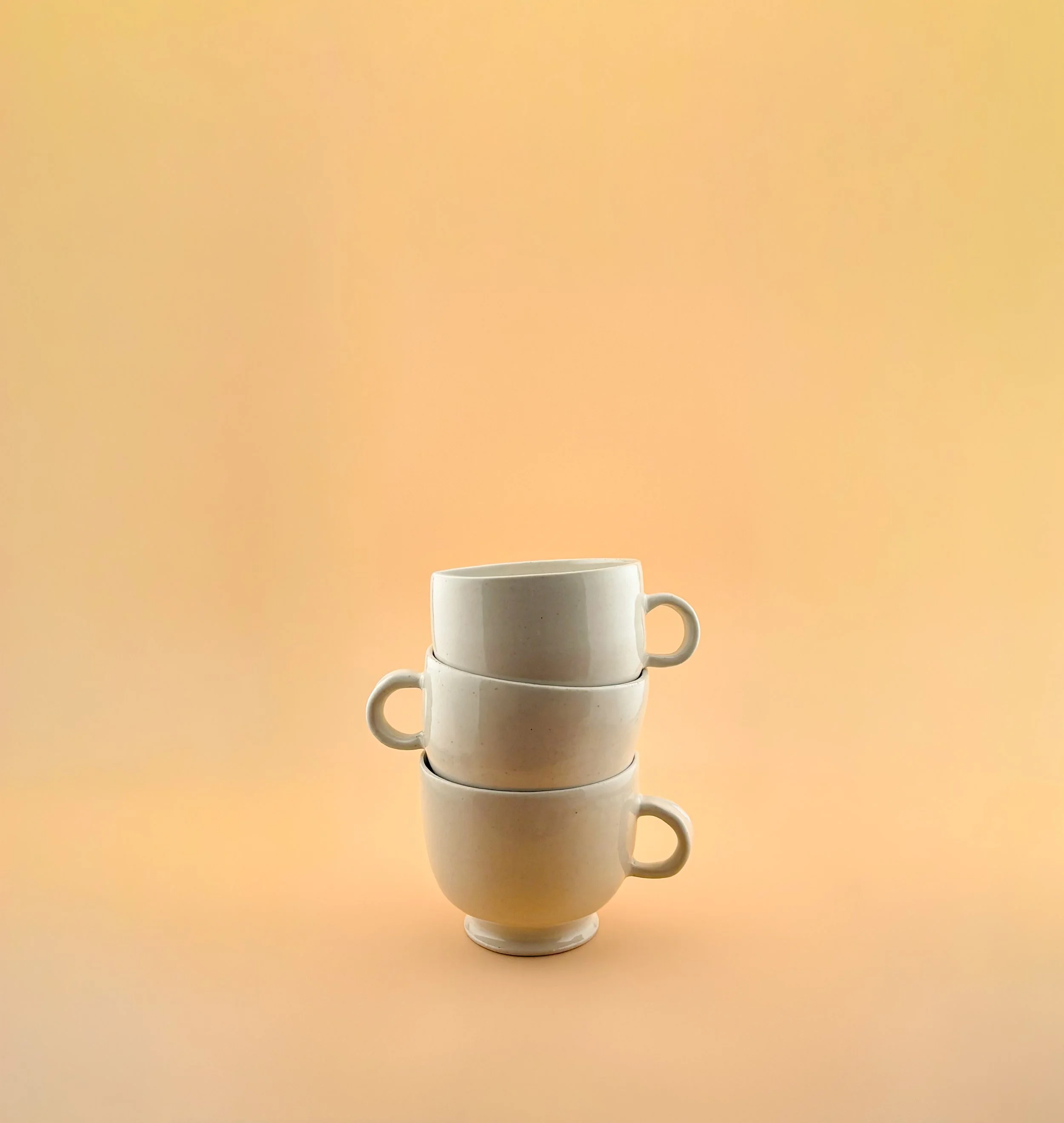 Stack of white ceramic matcha mugs showing form and handle silhouette.