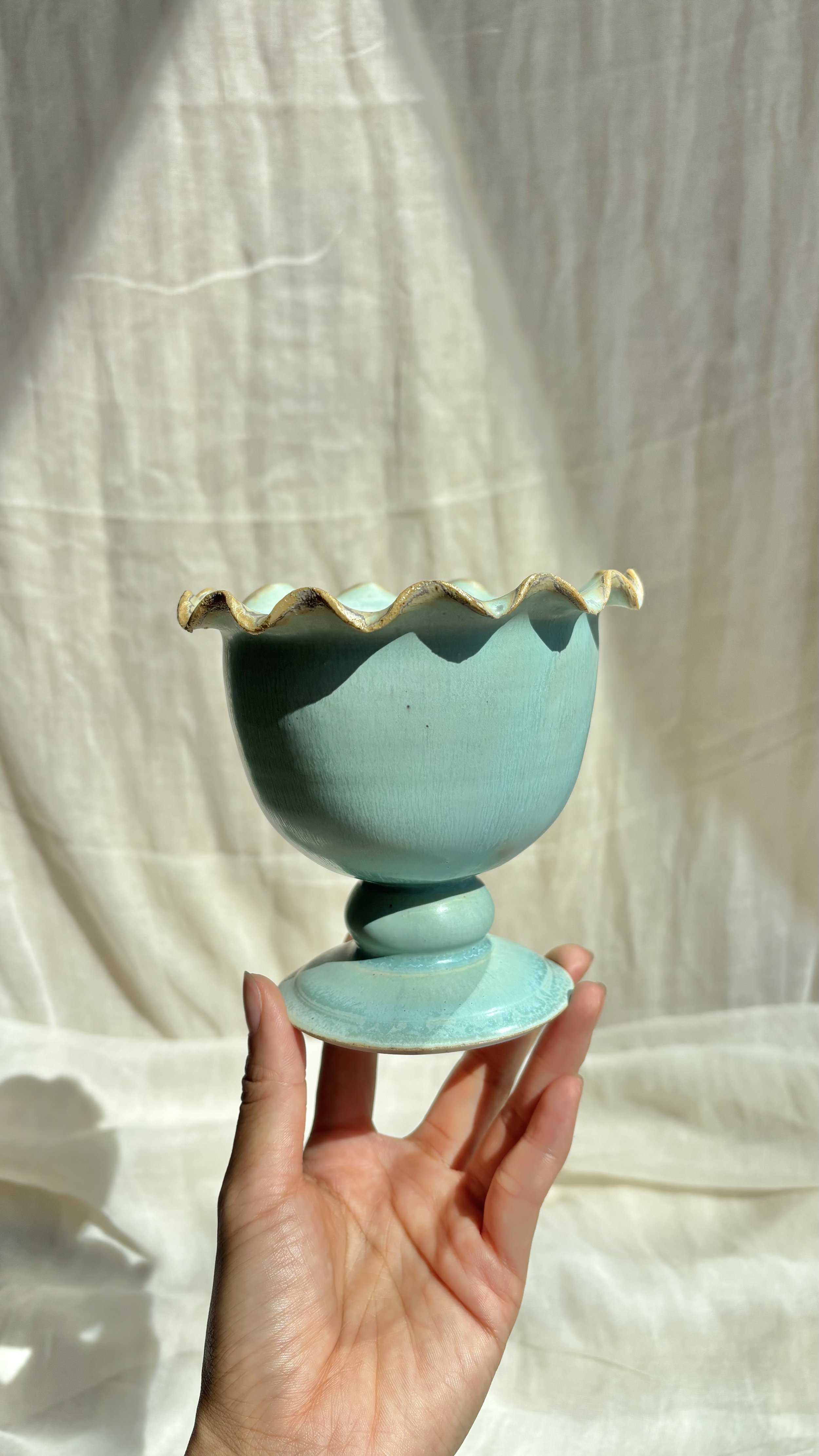Handmade ceramic mint ice cream sundae pedestal bowl with ruffled rim, held in hand.jpg