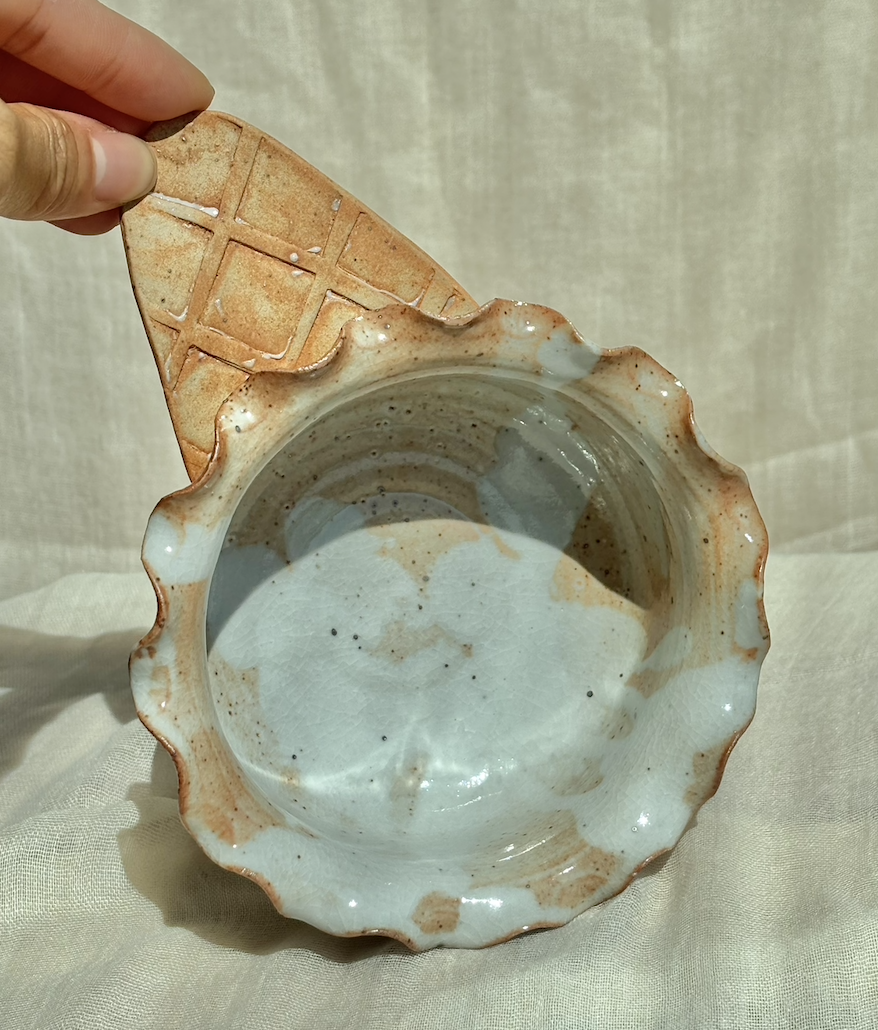 Handmade ceramic salted caramel waffle cone ice cream bowl with ruffled rim, held in hand.png