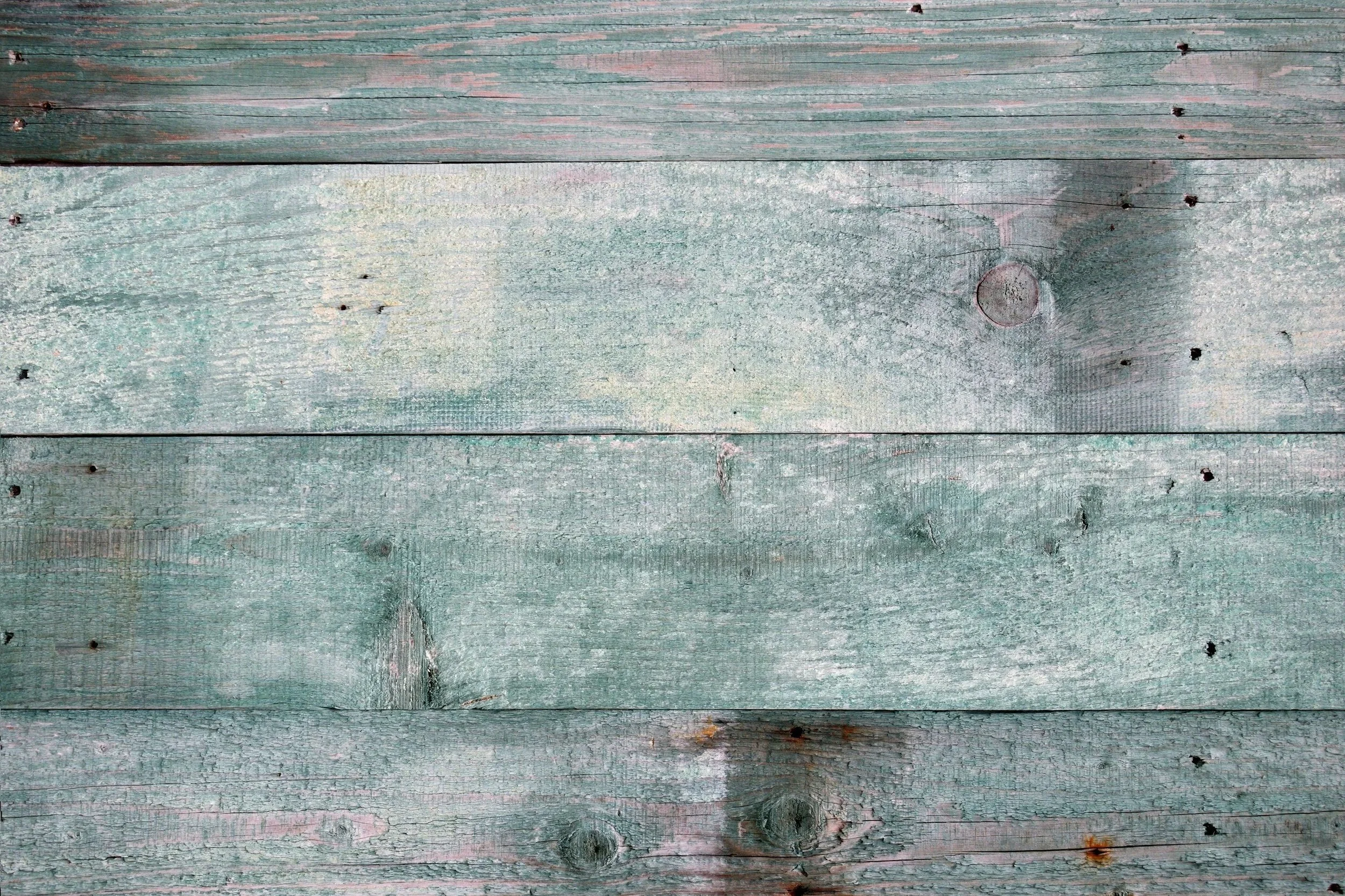 Weathered wooden planks painted in a faded light green, with visible knots, nails, and peeling paint.