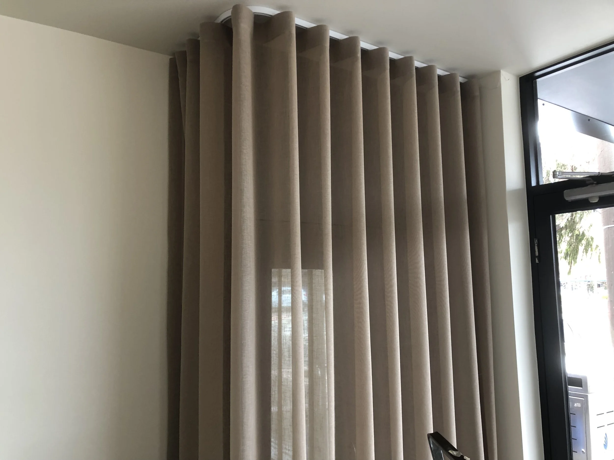Beige curtains hanging in front of a window in a room.