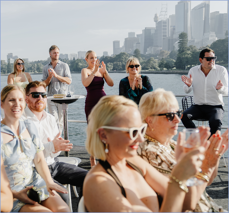 People on a boat enjoying a celebration with city skyline in the background.