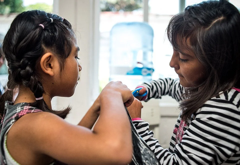 Niñas jugando con una cuerda en un interior con ventana.