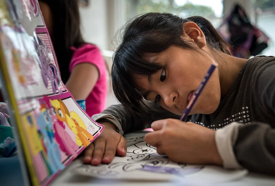 Niña coloreando un dibujo de My Little Pony en una mesa.