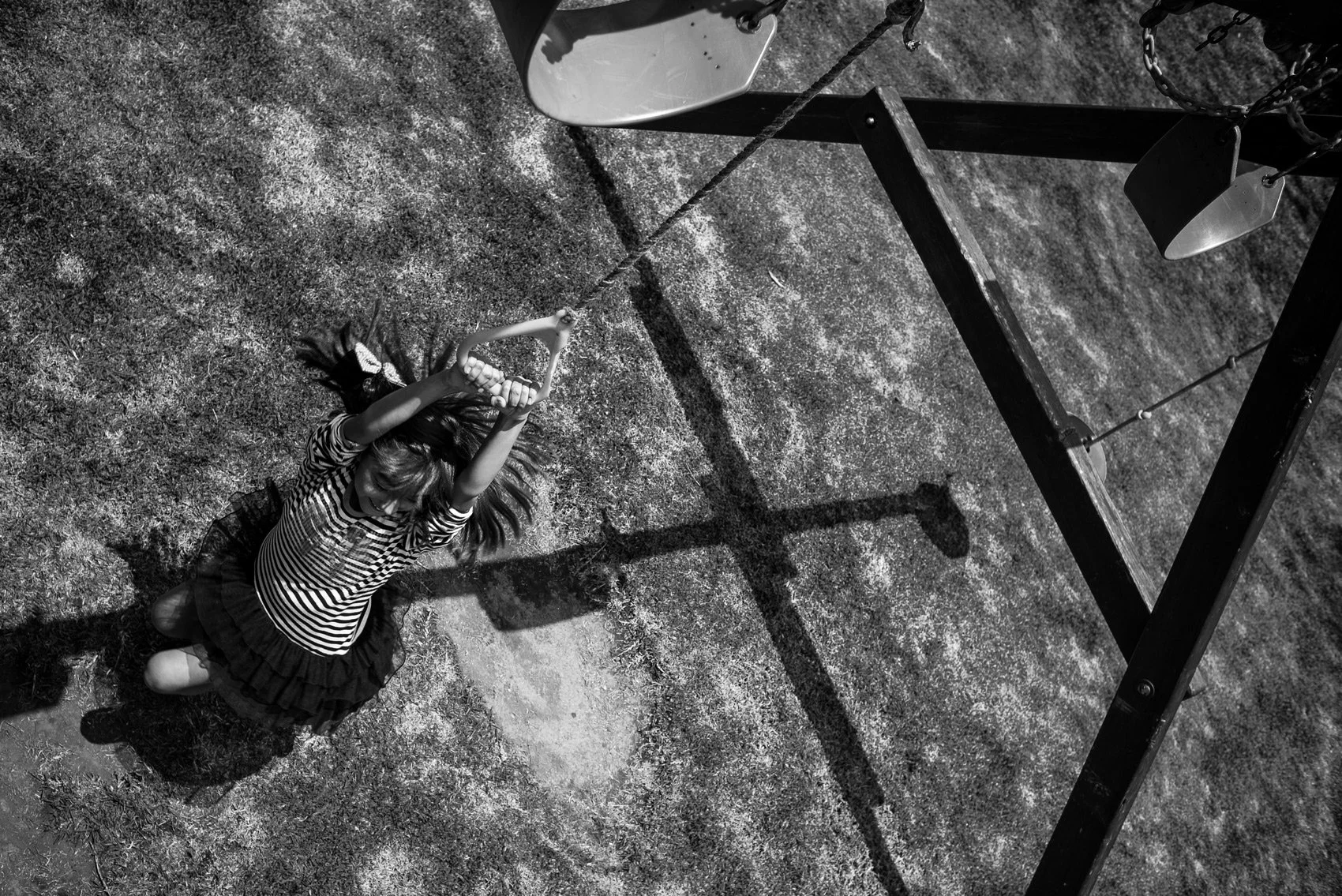 Una niña con vestido a rayas jugando en un columpio