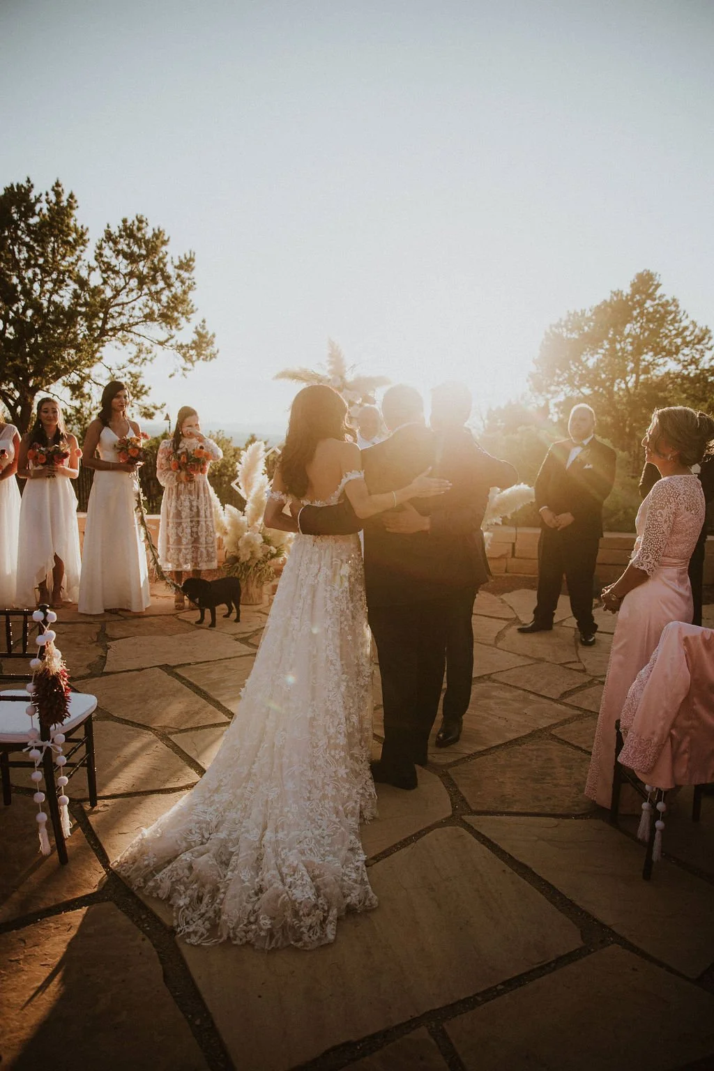 Bride and groom dancing at an outdoor wedding ceremony during sunset with bridesmaids and groomsmen in the background.