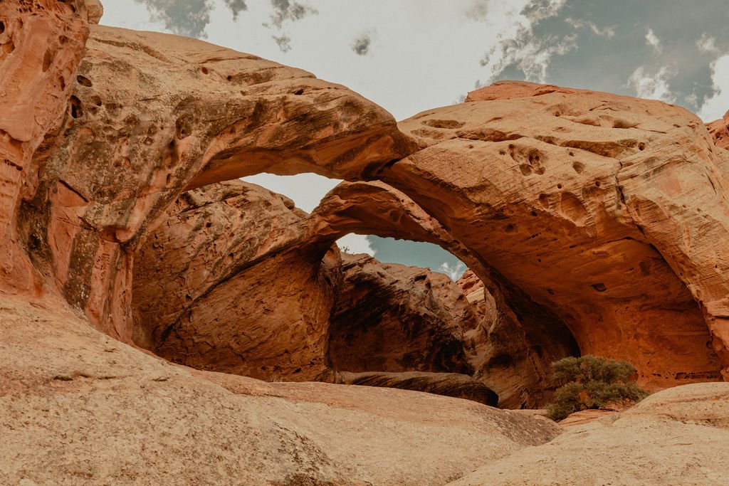 Rock formations forming natural arches in a desert landscape with a cloudy sky