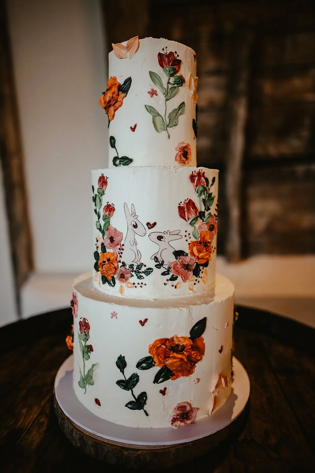 A three-tiered wedding cake decorated with floral and rabbit illustrations