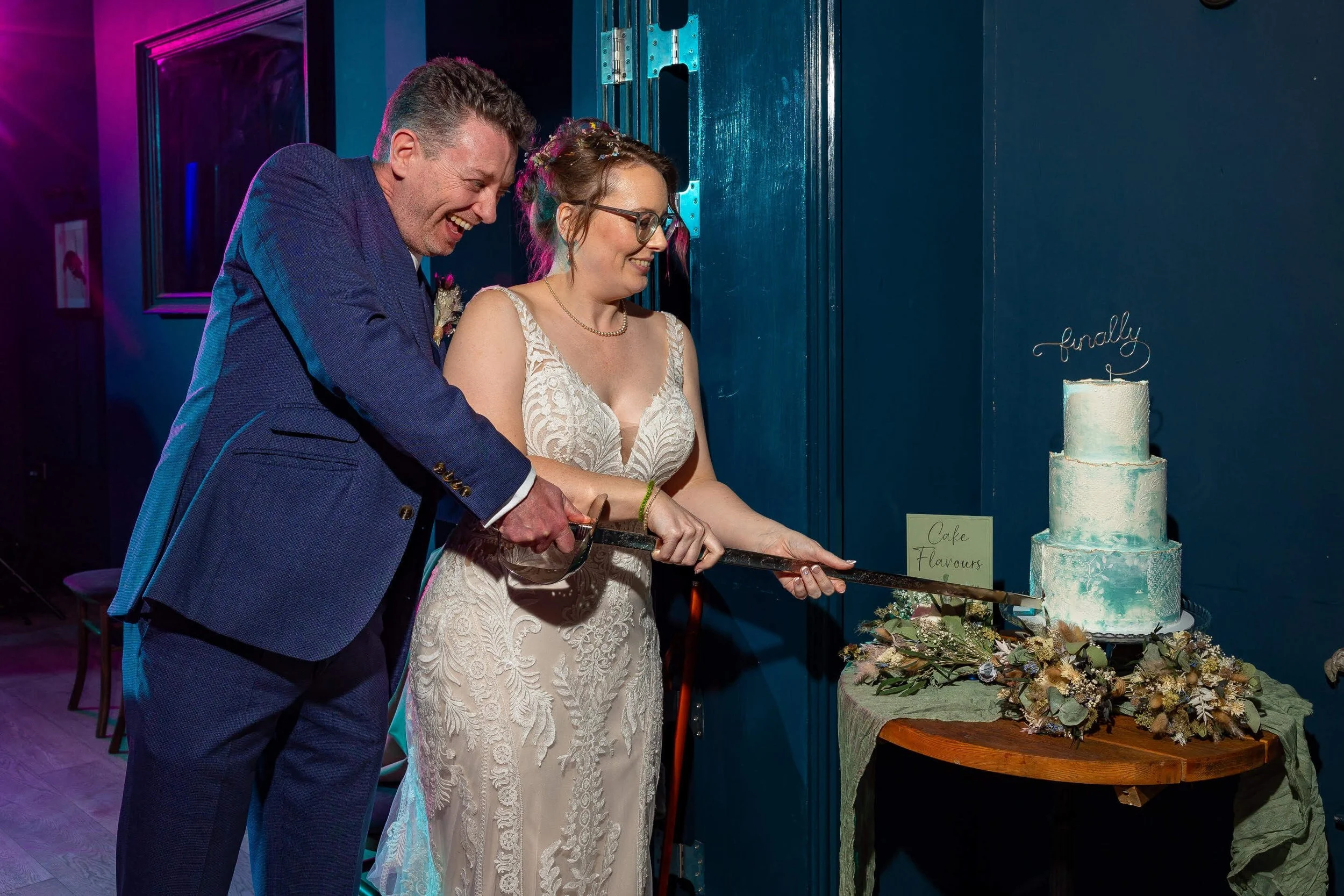 A bride and groom cutting a wedding cake together, smiling