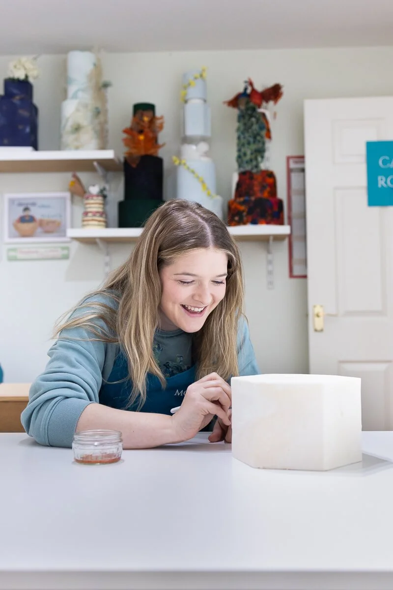 Ruth Moore sculpting a white cake in her cake room