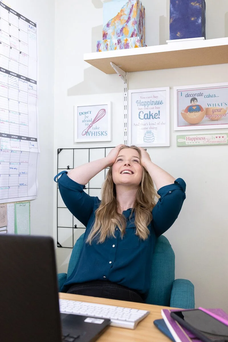 Ruth sitting at a desk, smiling and holding her head with both hands
