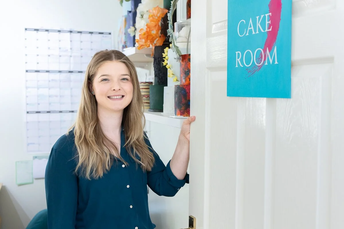 Ruth opening a door labelled 'Cake Room', leading into a home office