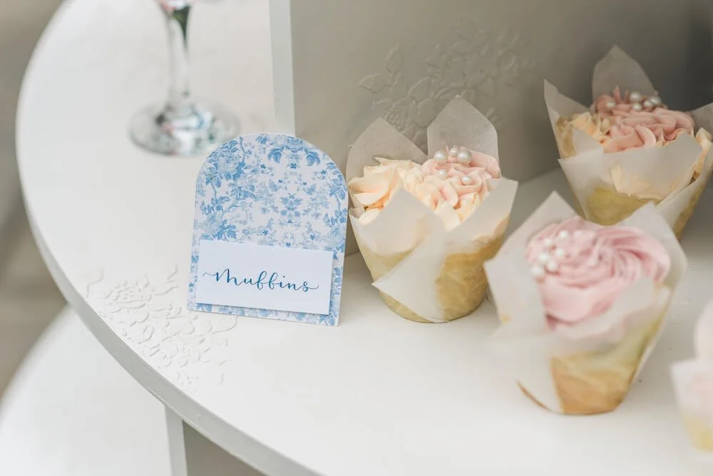 Cupcakes with pink and white icing, decorated with pearls, on a white dessert table