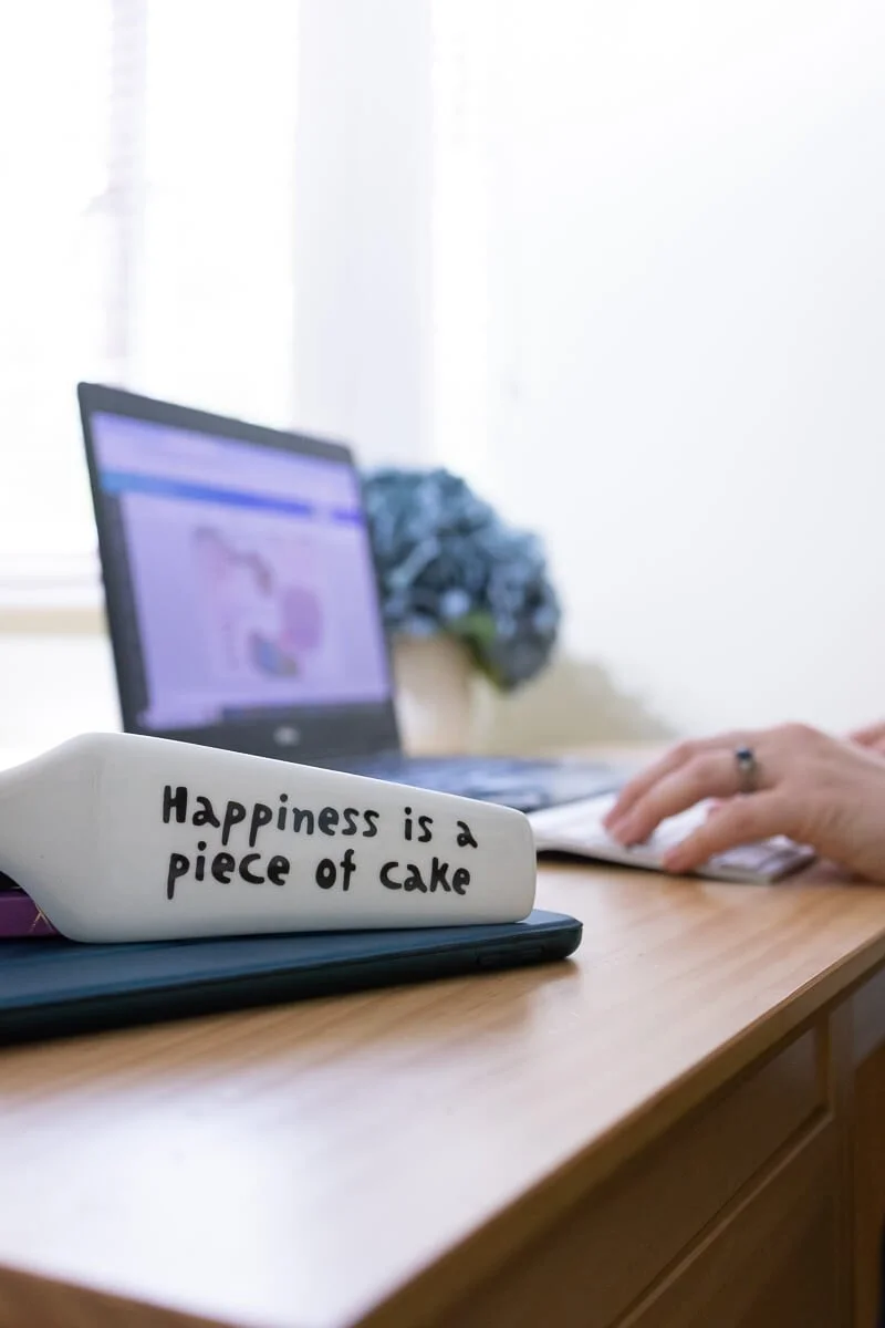 A white ceramic figurine with the quote 'Happiness is a piece of cake' written on it
