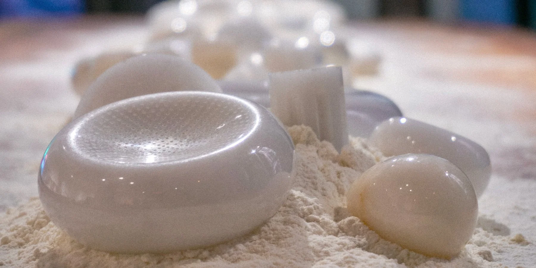 Close-up of white cooking or baking ingredients, including eggs and flour, on a wooden surface.